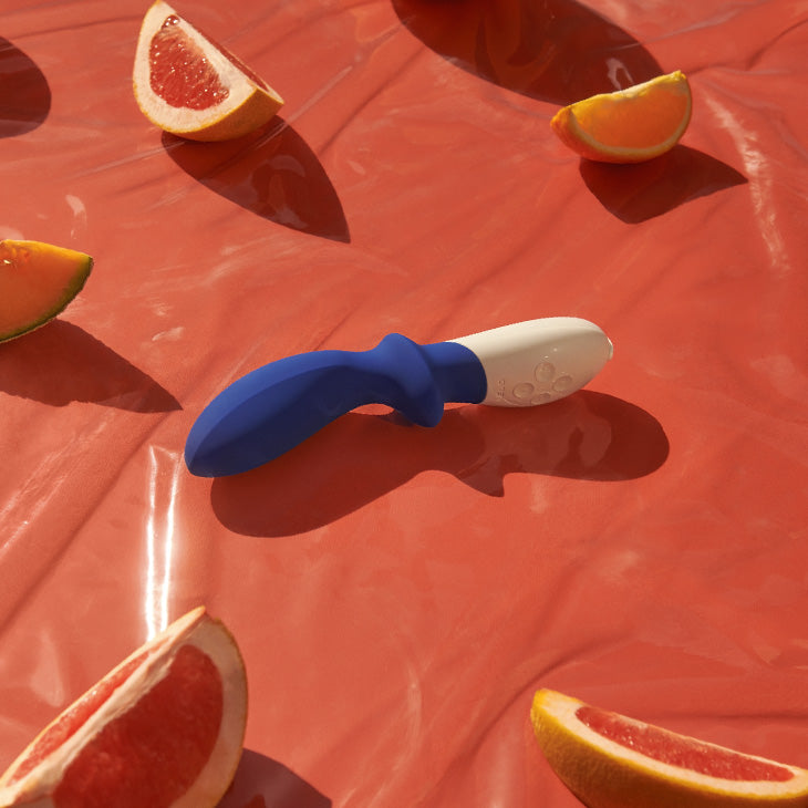LELO male sex toy on table with fruit in background.
