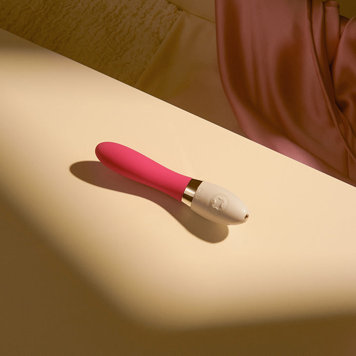 Pink LELO vibrator on bedside table.