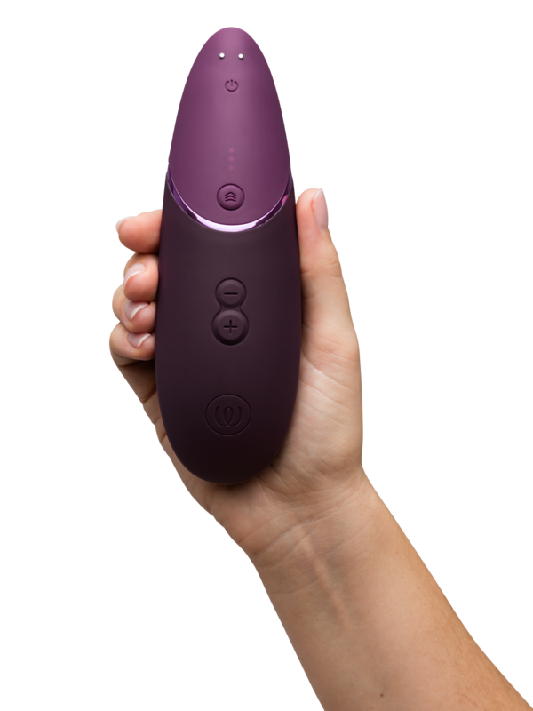 Womanizer Next held in hand with front intensity and power buttons visible.